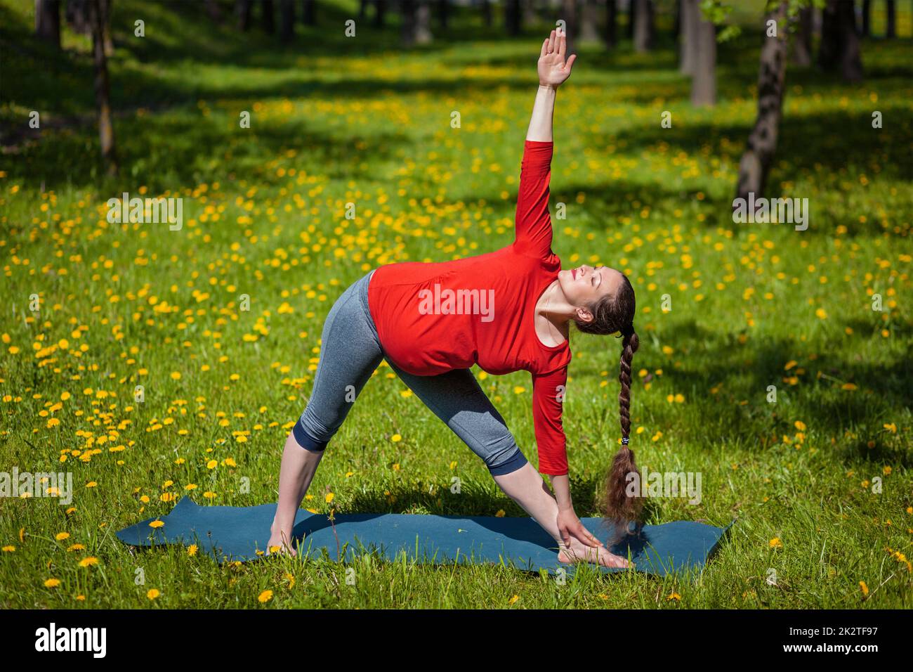 Schwangere Frau tun im freien Asana Utthita trikonasana Stockfoto