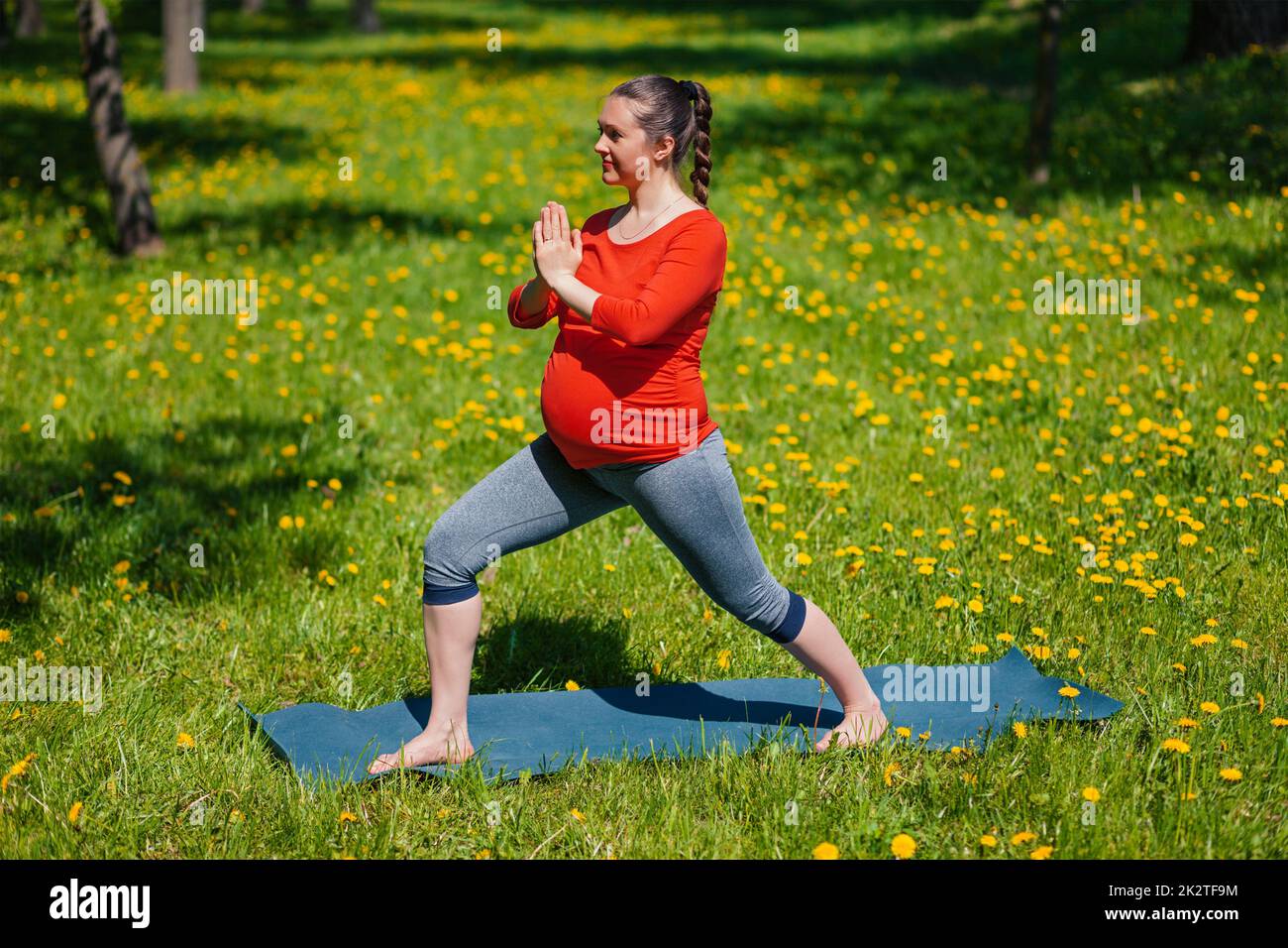Schwangere Frau tun Asana Virabhadrasana im freien Stockfoto