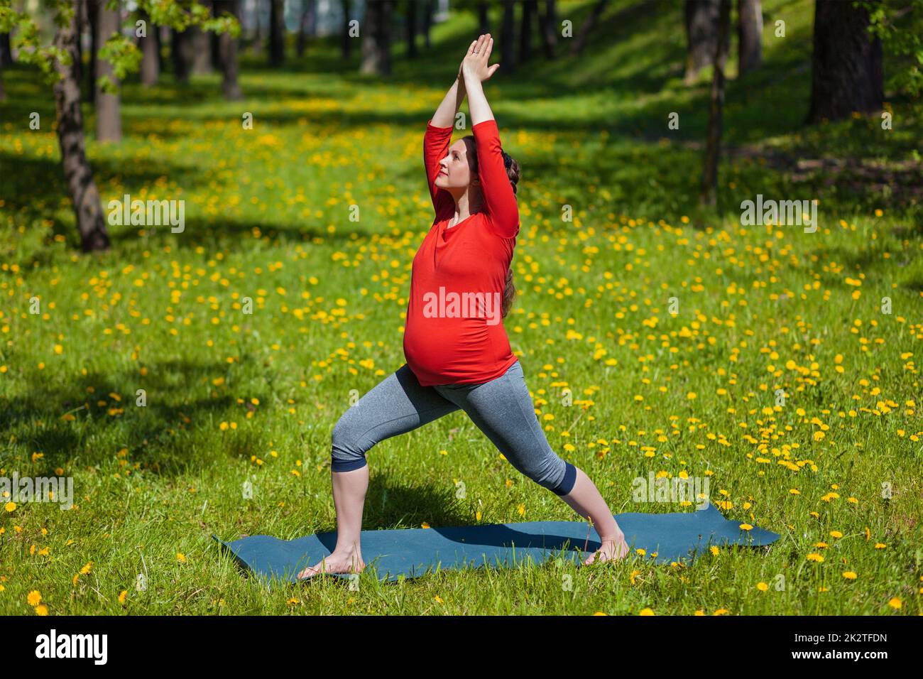 Schwangere Frau tun Asana Virabhadrasana im freien Stockfoto