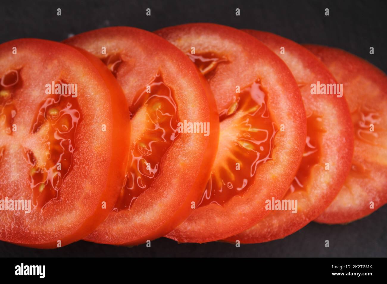 Nahaufnahme von Tomatenscheiben auf schwarzem Hintergrund. Blick von oben. Stockfoto