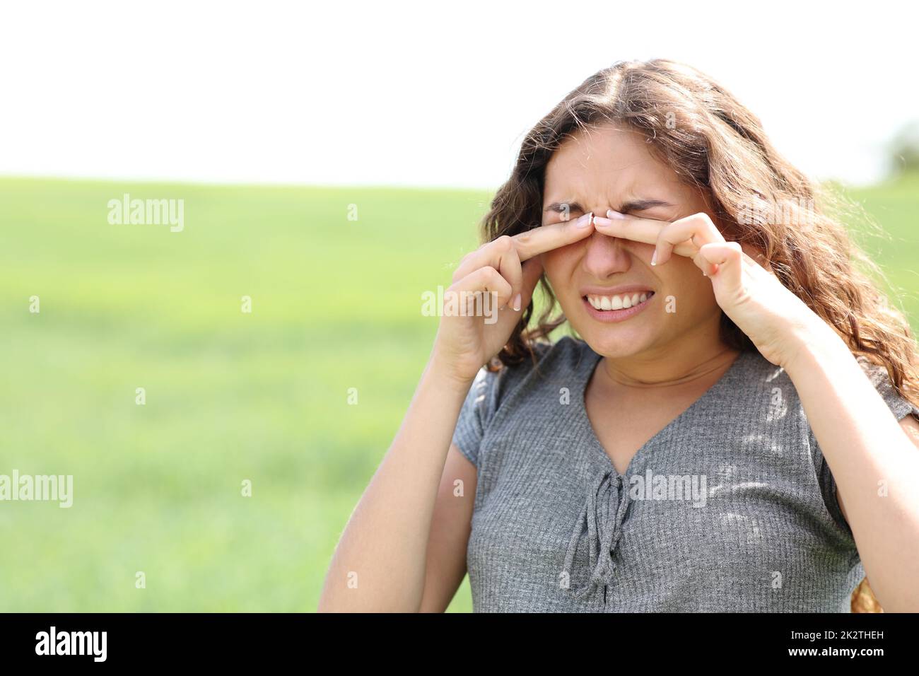 Eine Frau, die auf einem Weizenfeld die Augen kratzt Stockfoto