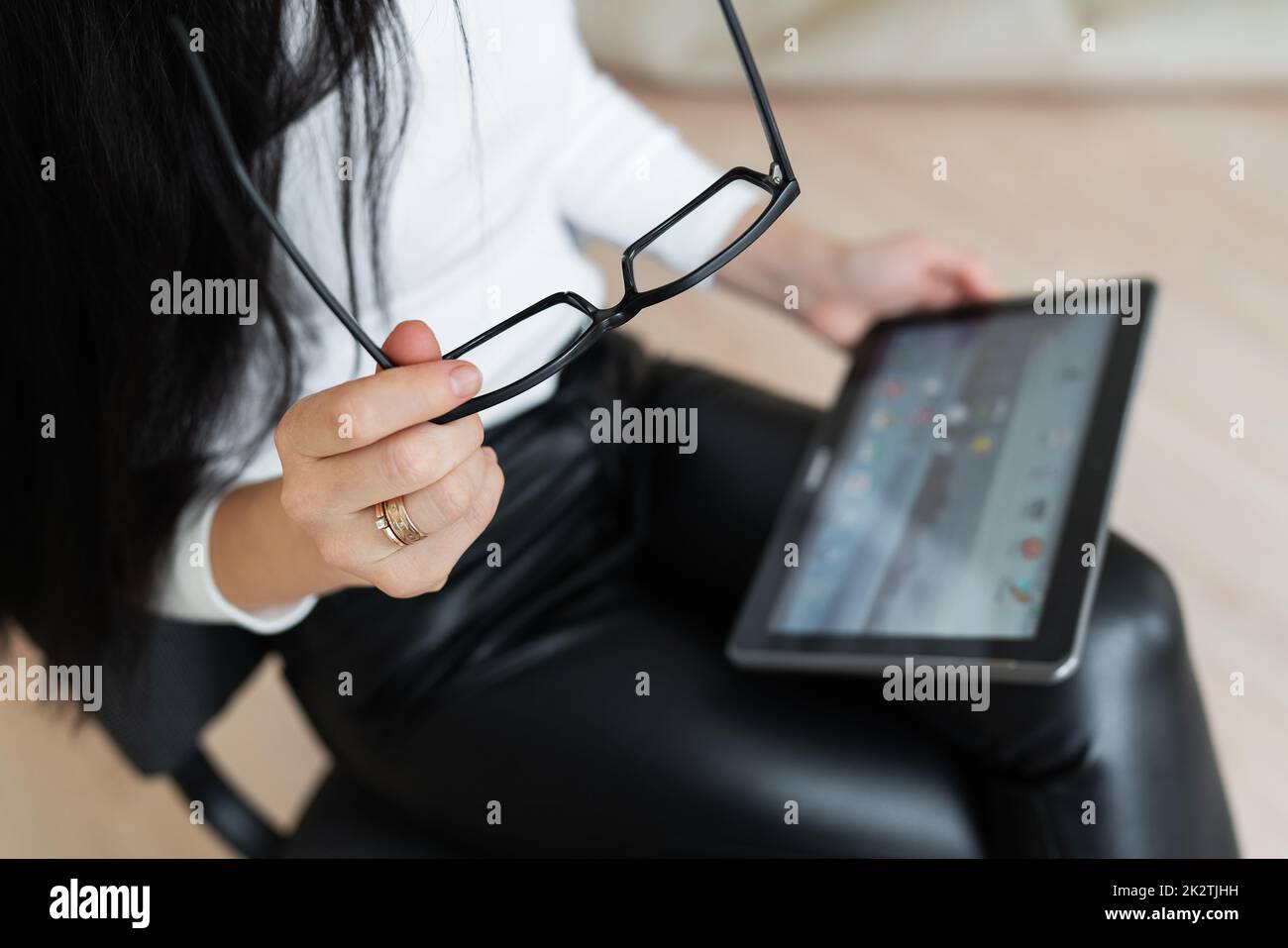 Ein junges Geschäftsmädchen löst Probleme online auf einem Tablet. Junge Frau, die in einer virtuellen Onlinekonferenz chattet. Das Konzept der Kommunikation ist nicht im Büro, sondern in der Online-Arbeit. Stockfoto