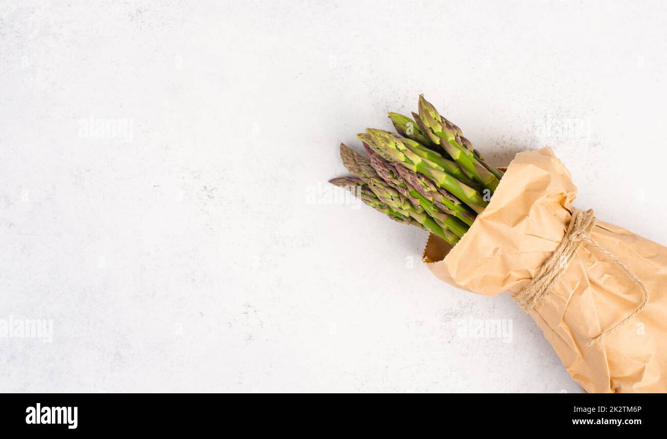 Frisches grünes Spargelbündel auf einem weiß strukturierten Tisch, Gemüse im Frühjahr, Gourmet-Küche, Kochen einer veganen Mahlzeit Stockfoto