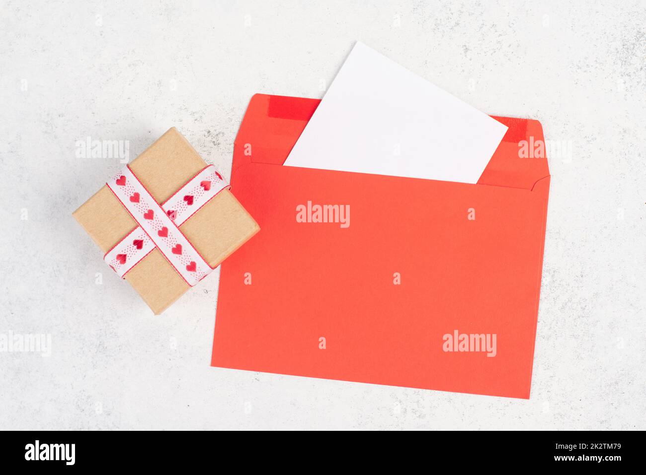 Roter Umschlag mit leerem Papier, Geschenkbox mit Herzen, texturiertem Hintergrund, Geburtstag, Muttertag, Vatertag und valintines-Grußkarte Stockfoto