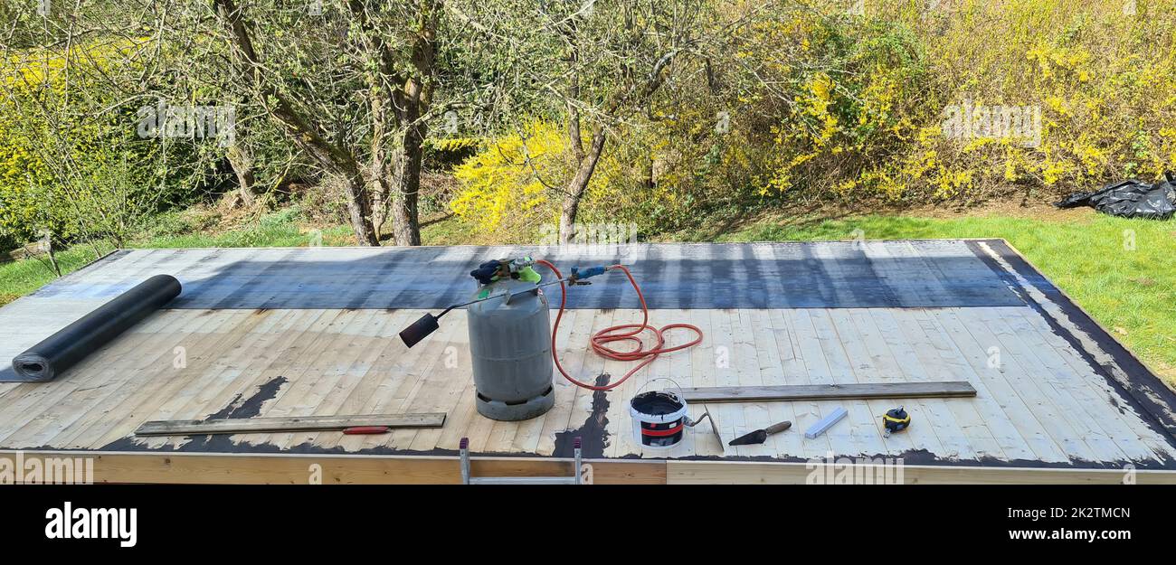 Reparatur von Flachdächern: Die Dachdecker schweißen die Dachabdichtung an. Dachsanierung mit Gasbrenner. Stockfoto