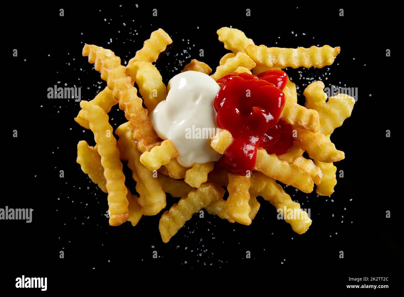 Leckeres Crinkle, gebraten mit Ketchup und Mayonnaise auf einem schwarzen Tisch Stockfoto