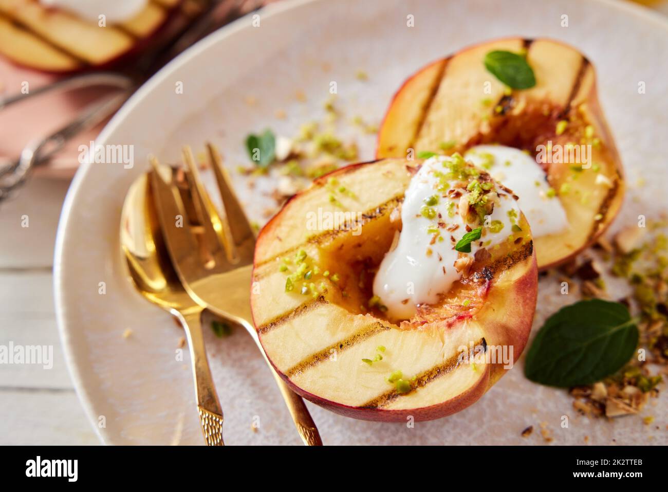 Leckere gegrillte Pfirsiche mit Joghurt und Pistazien auf dem Teller Stockfoto