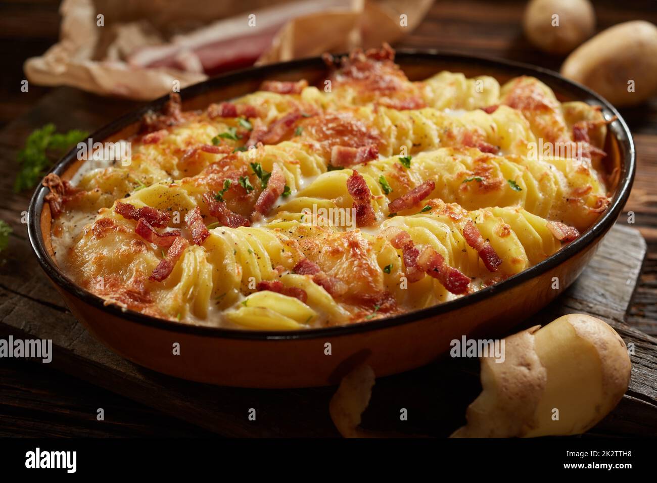 Leckeres cremiges Gratin mit Kartoffeln und Schinken, serviert auf dem Tisch in der Küche Stockfoto