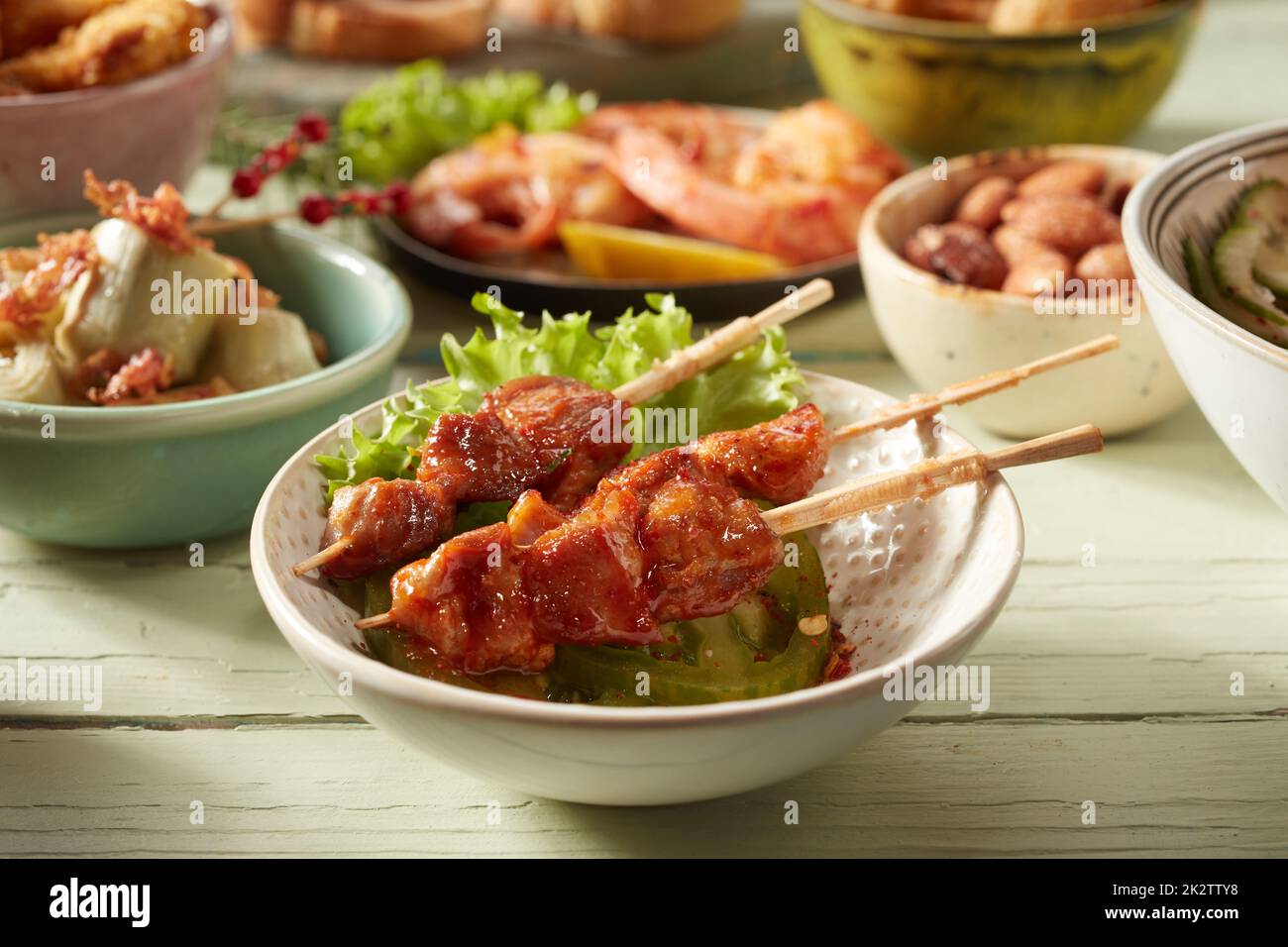 Köstliche Hähnchenspieße und verschiedene Speisen auf dem Tisch Stockfoto