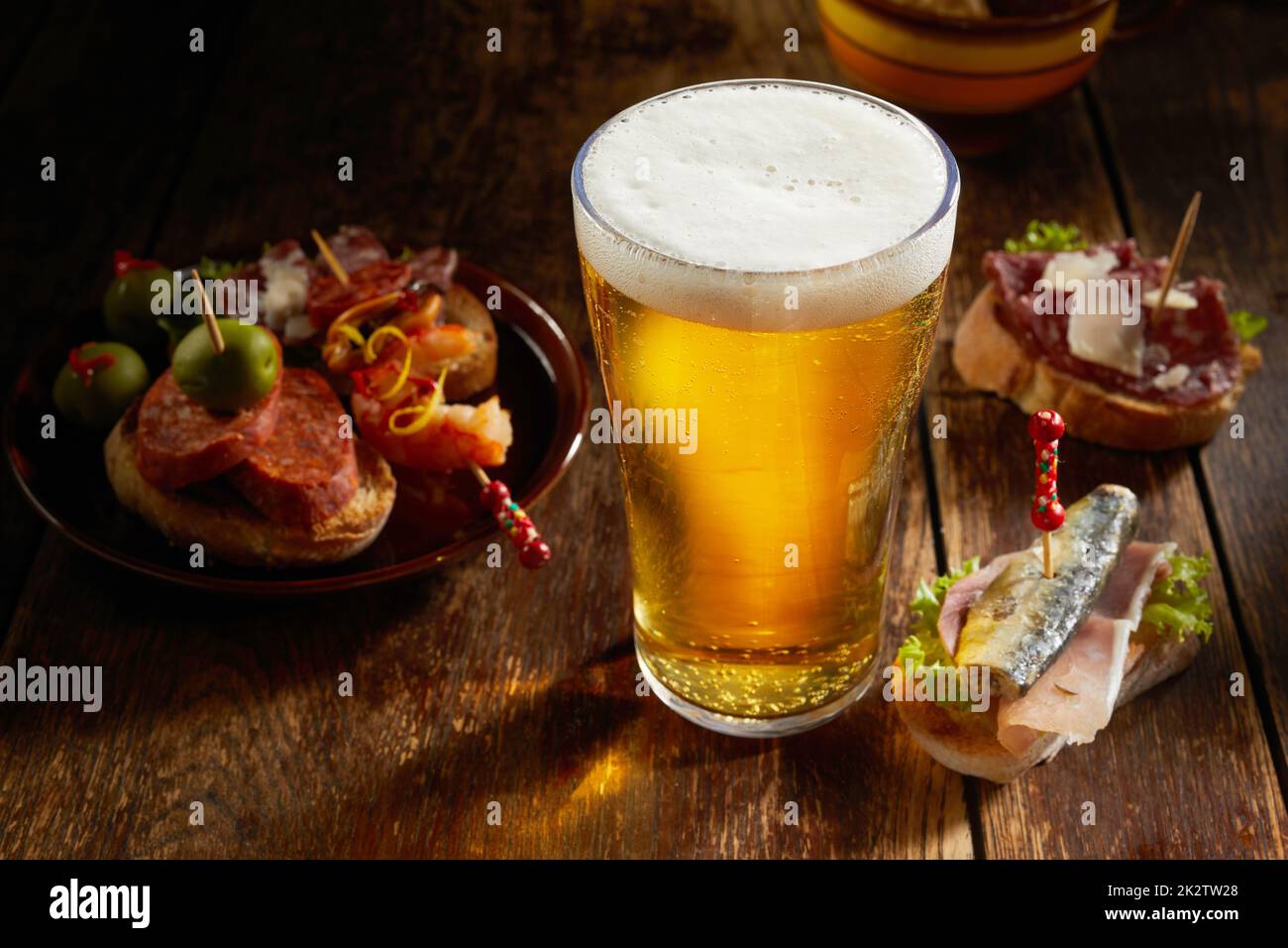 Leckere Auswahl an herzhaften Tapas serviert mit einem kalten Pint Bier Stockfoto