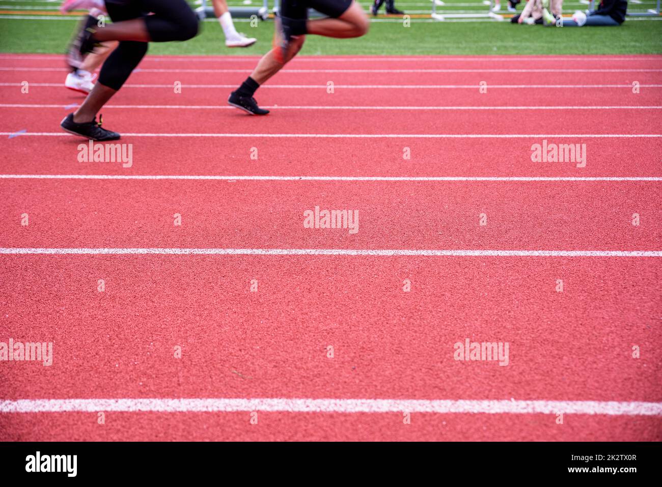Zwei Läufer laufen auf einer roten und einer Feldsportstrecke mit Spurmarkierungen Stockfoto