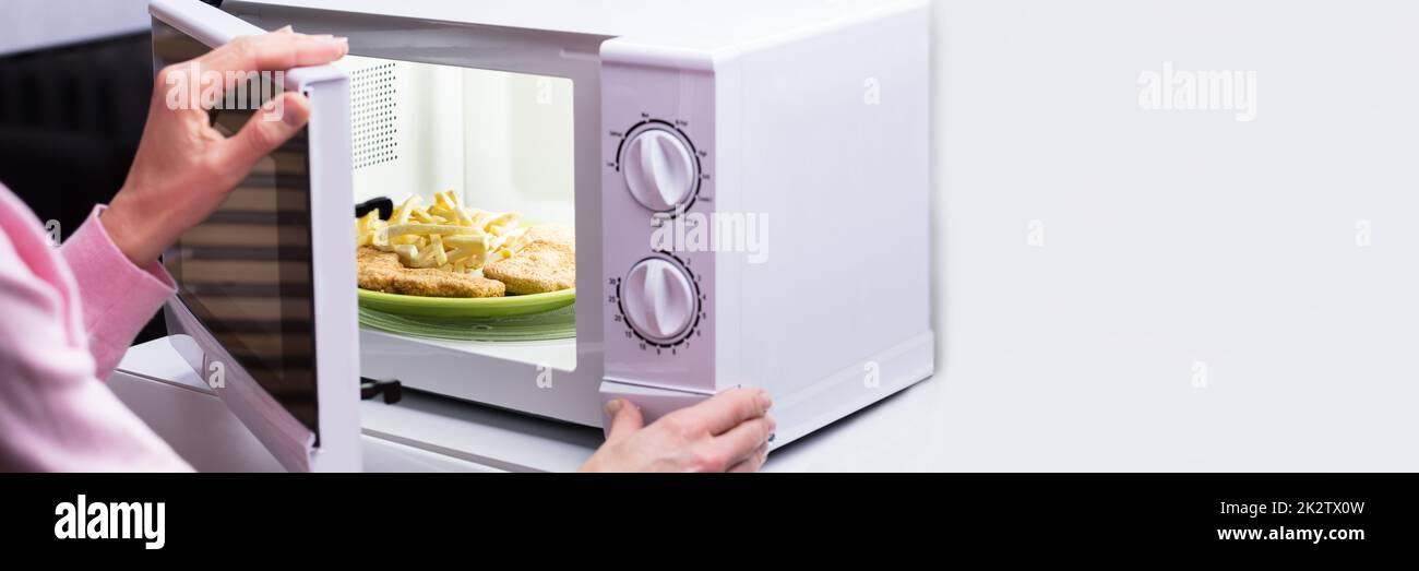 Frau Heizung Essen in der Mikrowelle Stockfoto