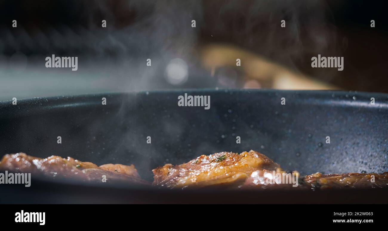Dampfgaren vom Steak in einer Pfanne. Konzept leckeres Essen. Dampfend Braten appetitliches Fleisch. Stockfoto