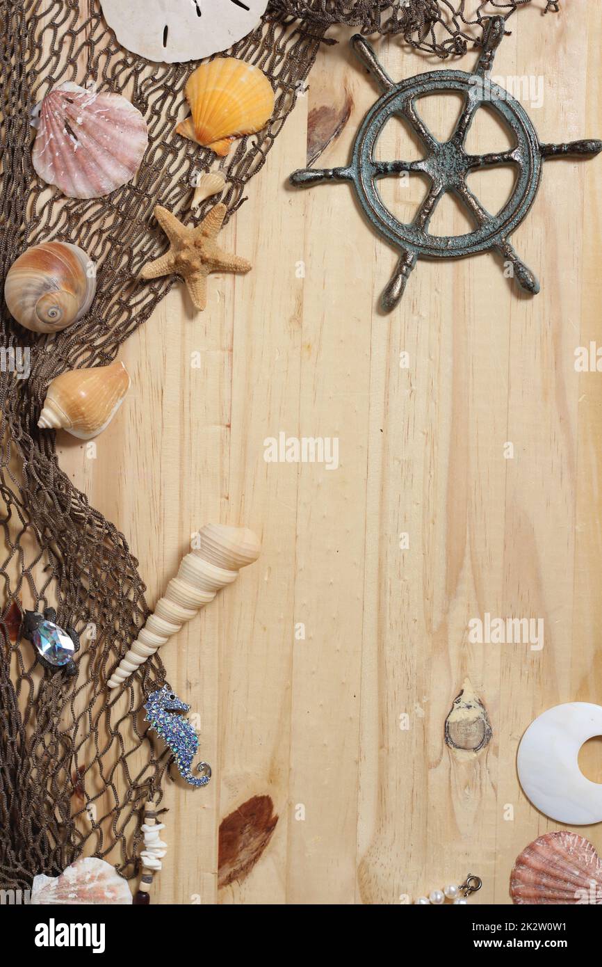 Captains Wheel mit Fischernetz und Meeresmuscheln auf Holzhintergrund Stockfoto