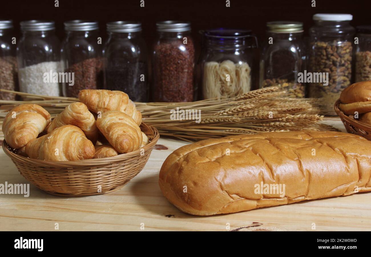 Frisch gebackenes Brot in der rustikalen Küche auf einem Holztisch mit Gläsern mit getrockneten Speisen im Hintergrund mit flachem DOF Stockfoto