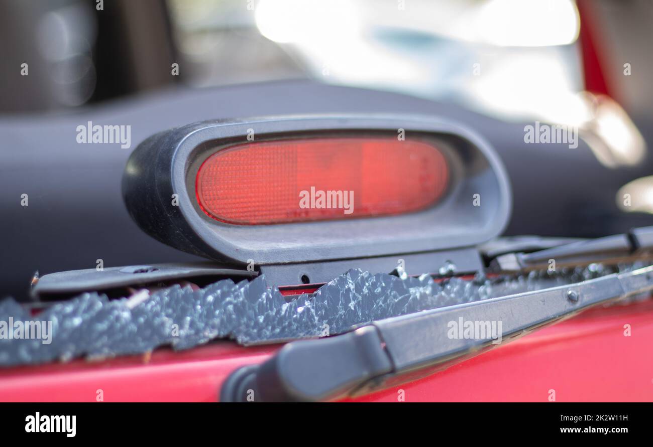 Ein Auto nach einem Unfall mit einer kaputten Heckscheibe. Zerbrochene Scheibe in einem Fahrzeug mit hinterer Bremsleuchte. Wrackteile im Innenraum, detaillierte Nahaufnahme eines beschädigten modernen Autos. Stockfoto