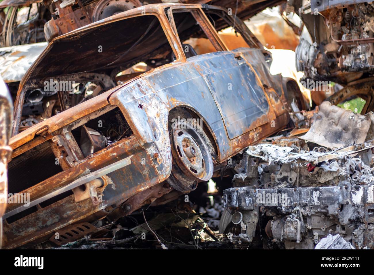 Autos nach dem Feuer. Eisenteile eines verbrannten Autos. Ausgebrannte Autos, die auf einer ruhigen Landschaft stehen. Explosion, die Folge eines Brandes. Kfz-Versicherungskonzept. Krieg Russlands gegen die Ukraine. Stockfoto