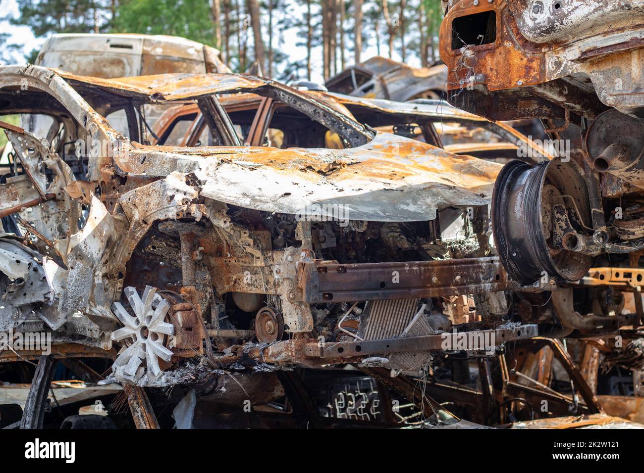 Autos nach dem Feuer. Eisenteile eines verbrannten Autos. Ausgebrannte Autos, die auf einer ruhigen Landschaft stehen. Explosion, die Folge eines Brandes. Kfz-Versicherungskonzept. Krieg Russlands gegen die Ukraine. Stockfoto