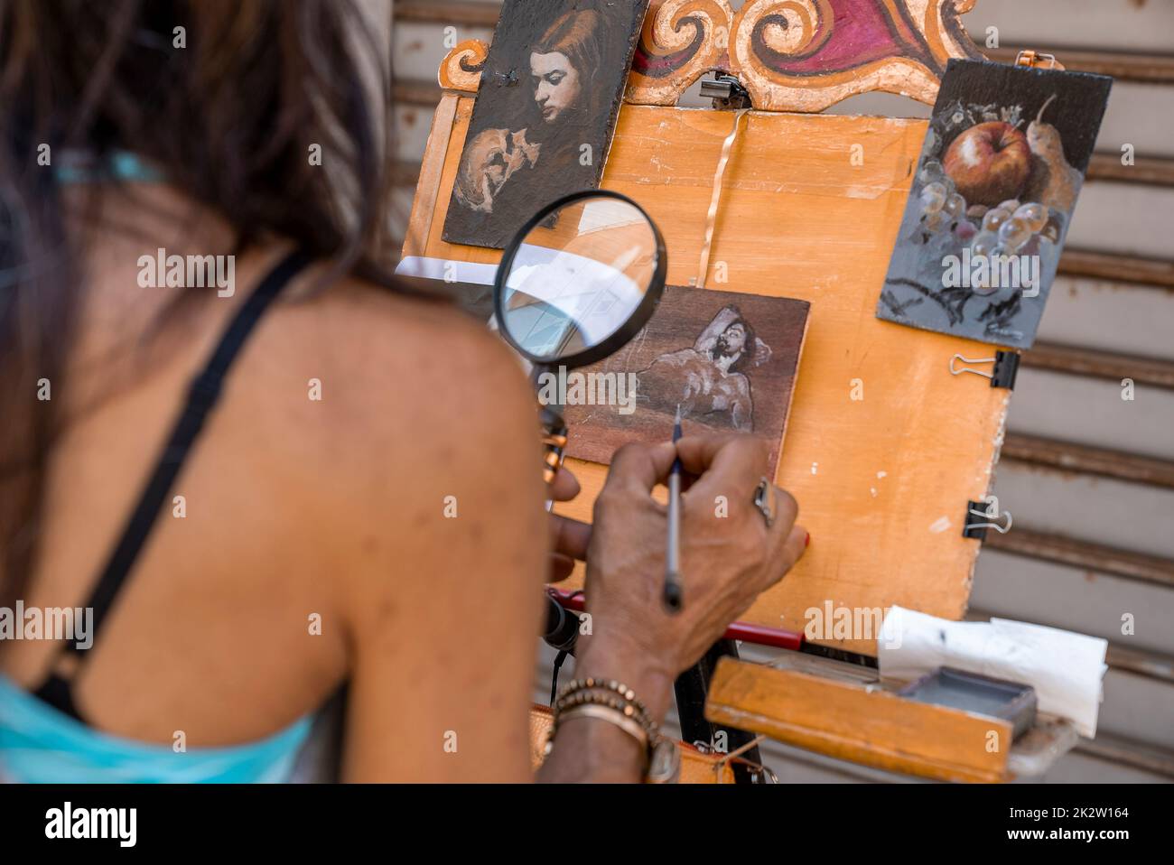 Frau malte Details auf kleinen Leinwänden vor dem Geschäft auf dem Markt in der Altstadt Stockfoto
