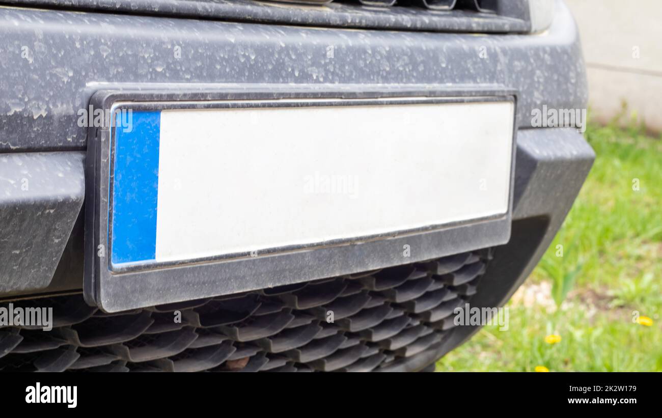 Fahrzeugnummer ohne Buchstaben und Zahlen auf der Stoßstange. Leeres weißes Nummernschild vor dem Auto, alle Logos entfernt, Nahaufnahme. Das vordere rechteckige Nummernschild eines Fahrzeugs auf der Straße. Stockfoto