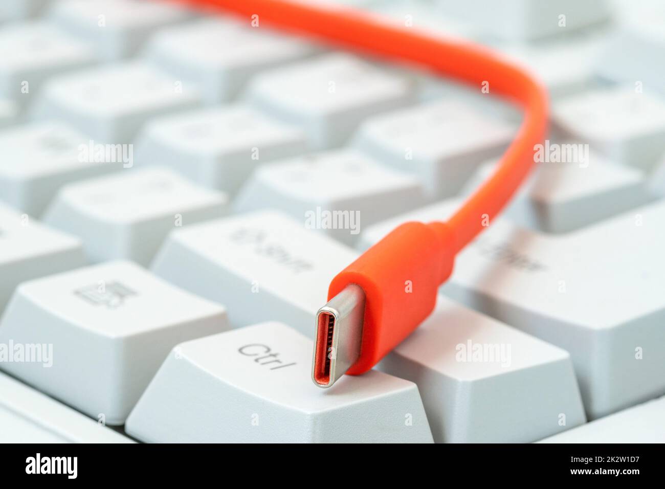 Das orangefarbene Kabel mit dem Typ-c-Anschluss befindet sich auf der weißen Tastatur Stockfoto