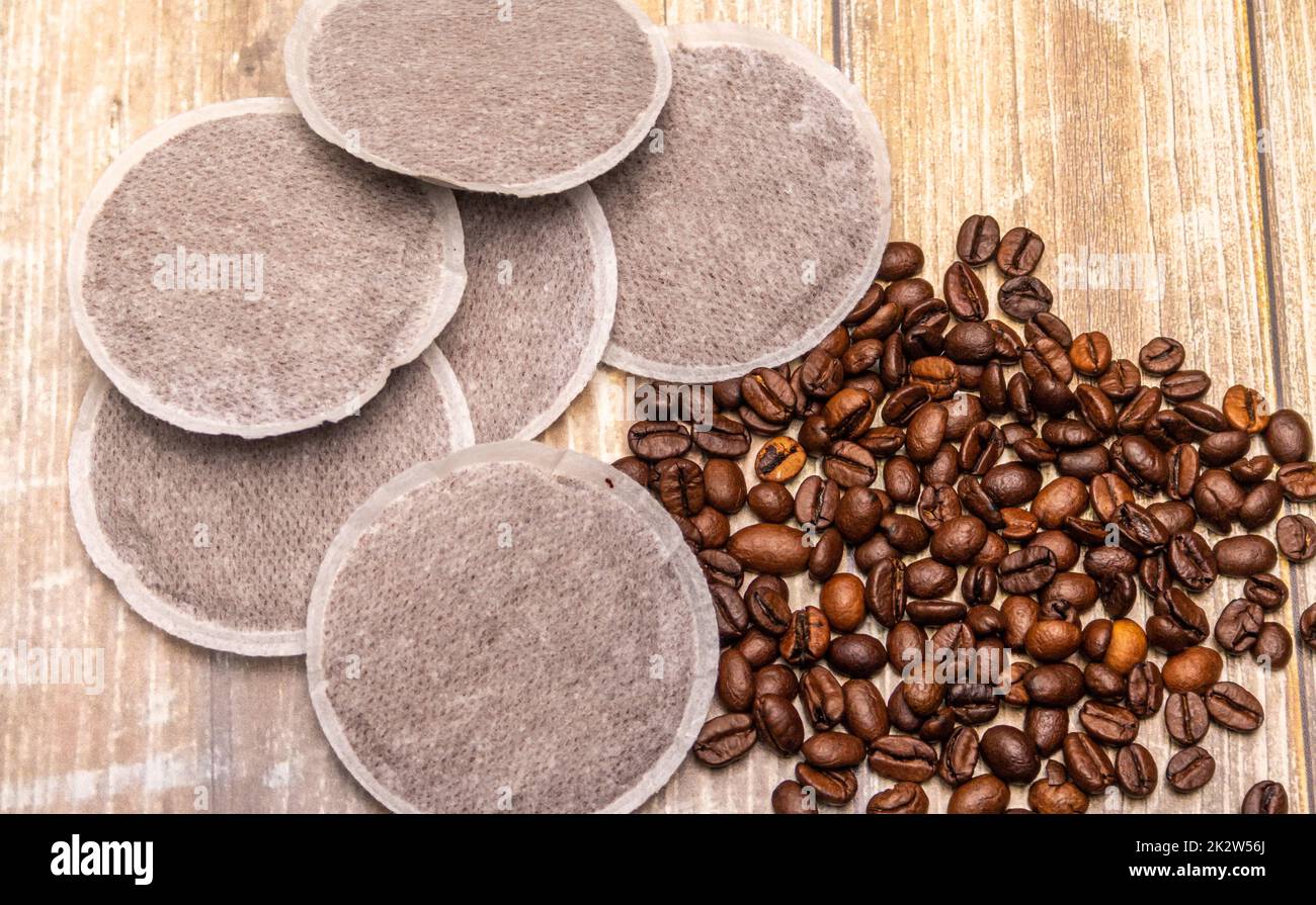 Kaffeepads und Kaffeebohnen auf einer Holzfläche Stockfoto