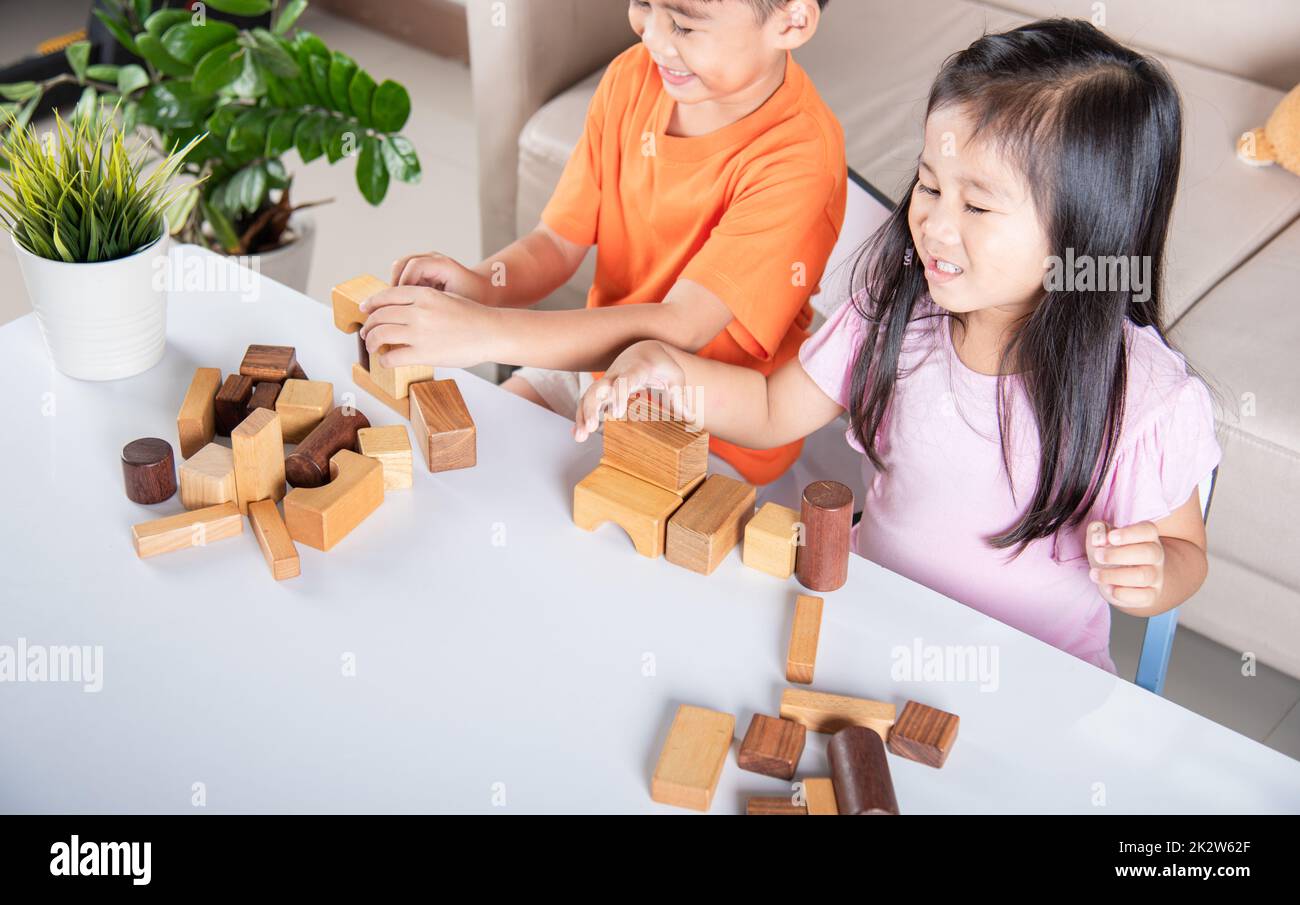 Kinder Junge und Mädchen spielen mit Bauunternehmer Holzblock Gebäude Stockfoto