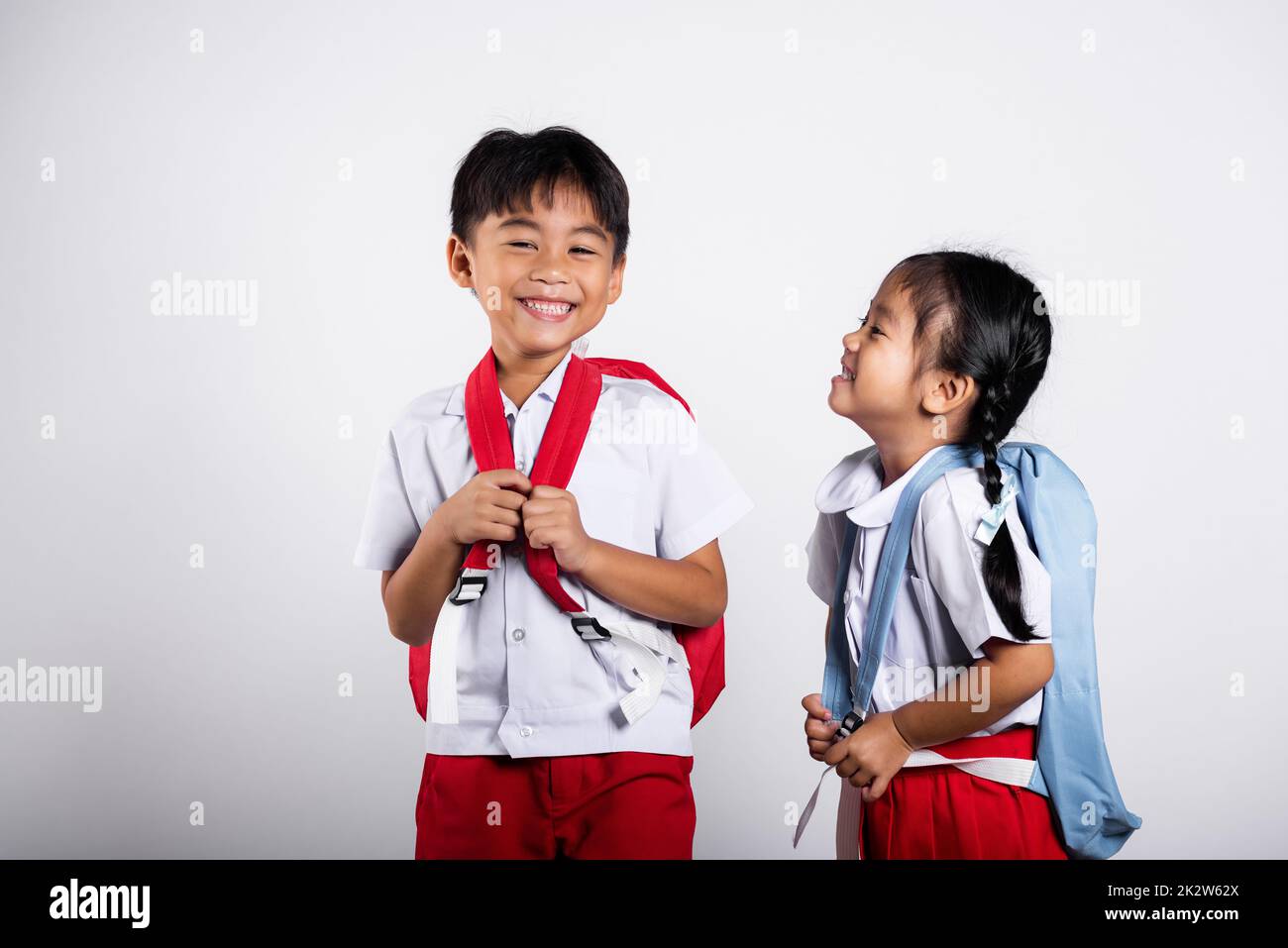 Zwei asiatische Schüler Mädchen Junge Schulkinder Bruder Schwester lächeln fröhliche Studentin thai Uniform rote Hosen Rock Stockfoto