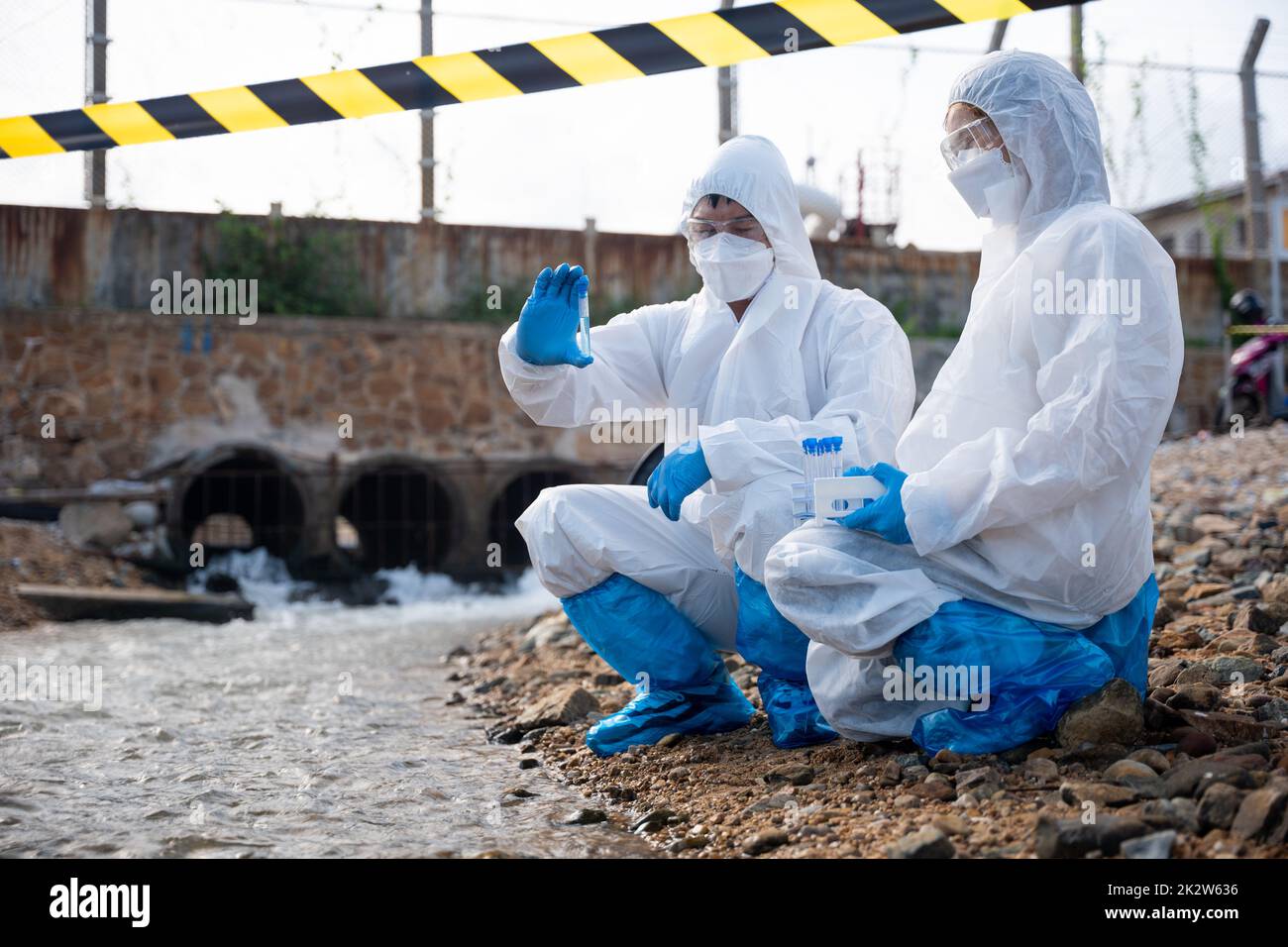 Ökologe, die Wasser aus dem Fluss mit einem Reagenzglas entnehmen Stockfoto