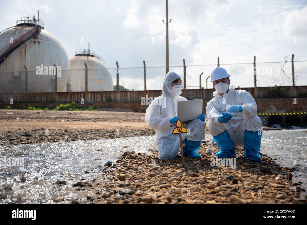 Biologe tragen Schutzanzug und Maske sammelt Abwasserproben aus der Industrie Stockfoto