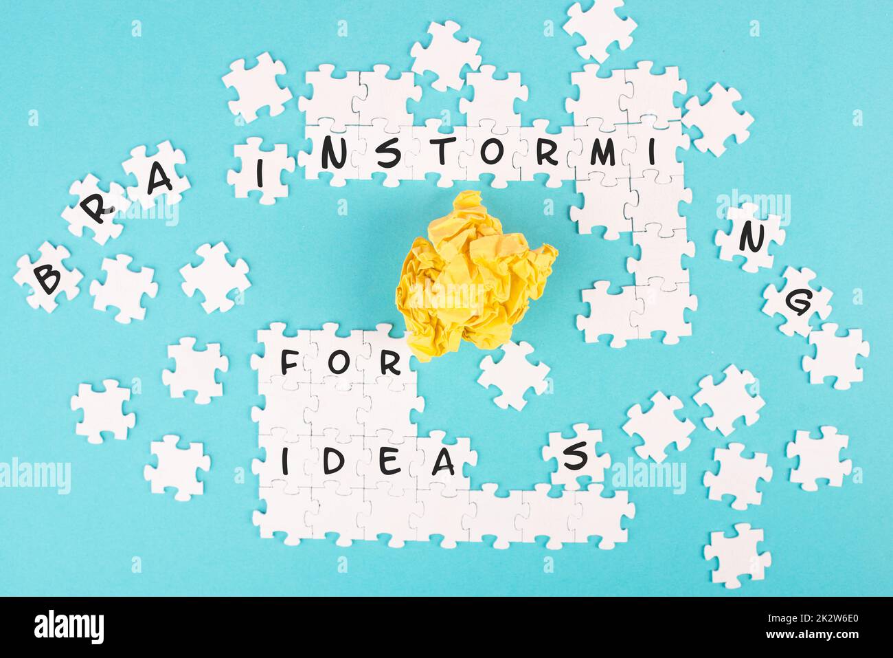 Puzzle auf blauem Hintergrund, gelbes, zerbröckeltes Papier, Wortwahl für Ideen stehen auf den Puzzleteilen, Geschäftskonzept, Zusammenarbeit als Team Stockfoto