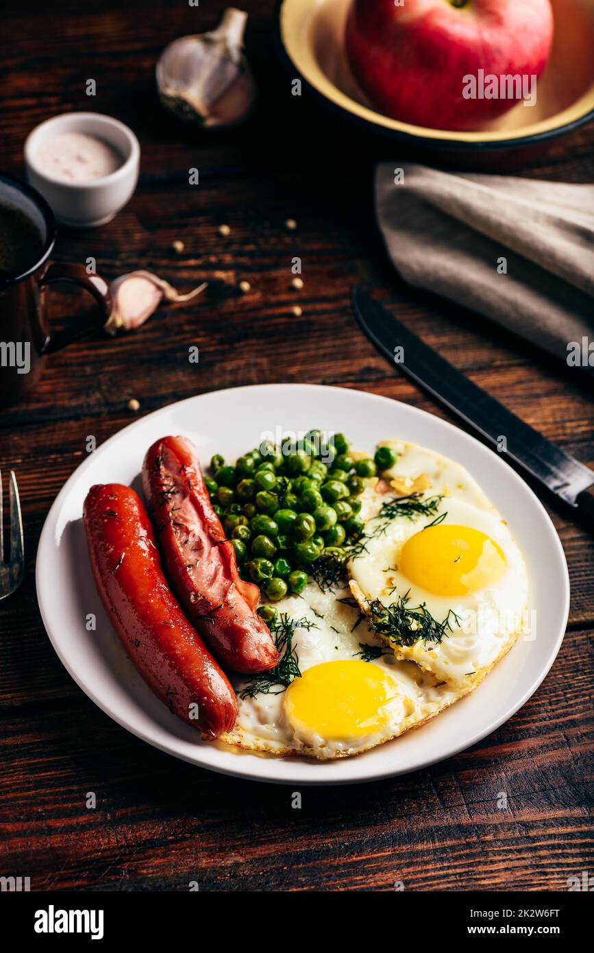 Frühstück mit Spiegeleiern, Würstchen und grünen Erbsen Stockfoto