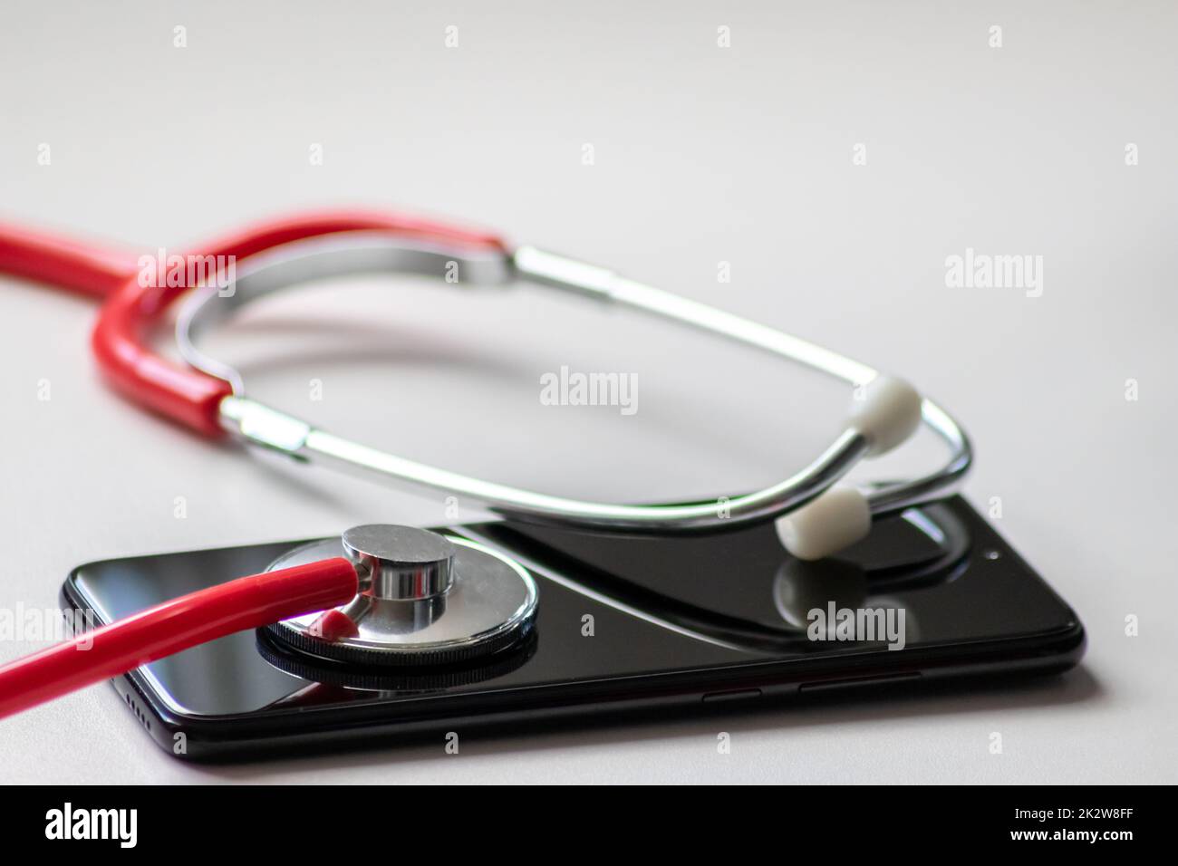 Rotes Stethoskop auf schwarzem Smartphone stellt Gesundheitsdaten und digitale Patientenakten mit mobilen Geräten für digitale Ärzte und digitale diagnostische Behandlung mit modernen Geräten und Technologien dar Stockfoto