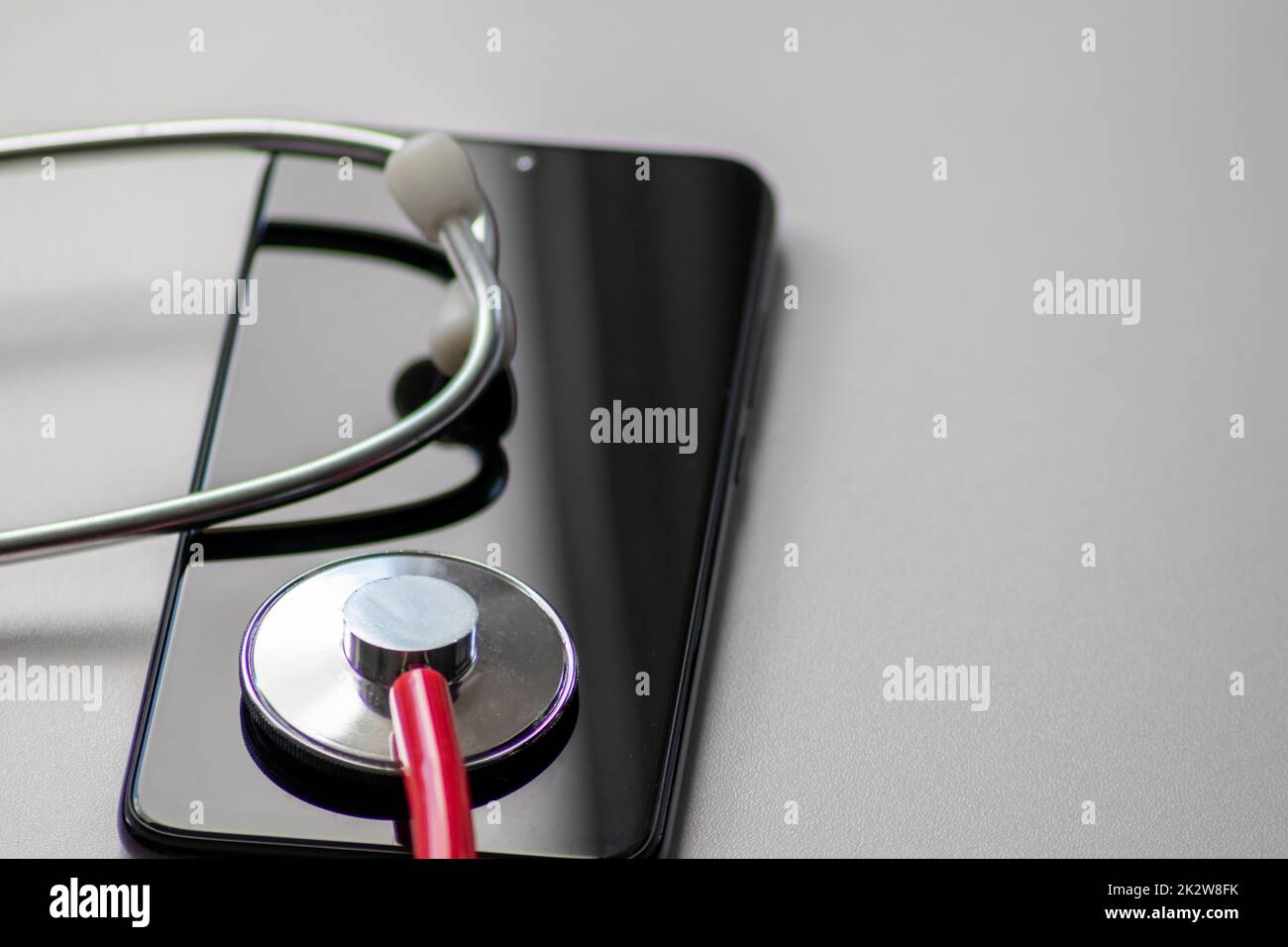 Rotes Stethoskop auf schwarzem Smartphone stellt Gesundheitsdaten und digitale Patientenakten mit mobilen Geräten für digitale Ärzte und digitale diagnostische Behandlung mit modernen Geräten und Technologien dar Stockfoto