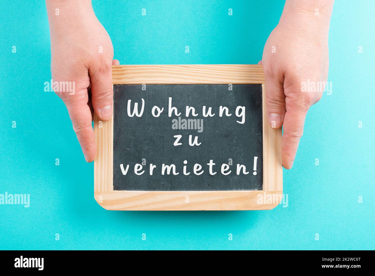 Mit einer Tafel in den Händen steht die Mietwohnung in deutscher Sprache auf dem Schild und zieht in ein neues Zuhause, eine Immobilie Stockfoto