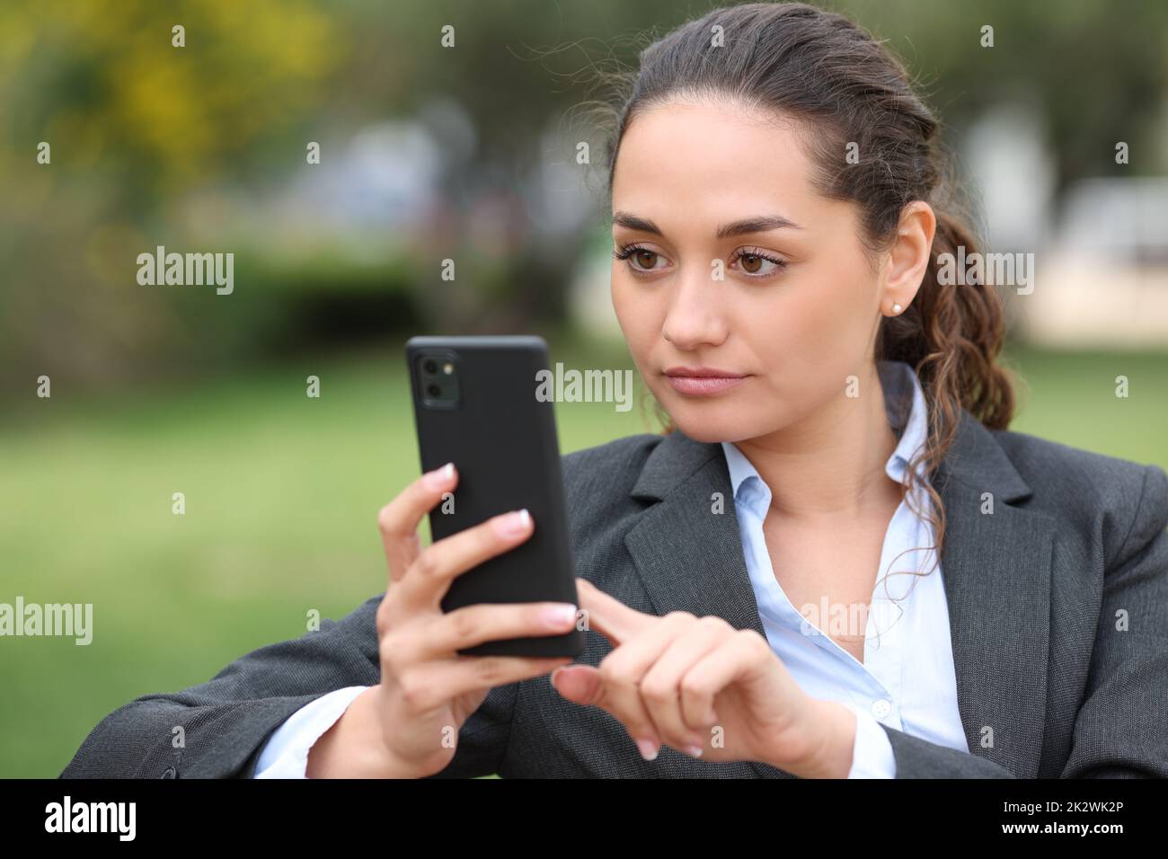 Eine seriöse Geschäftsfrau, die im Park telefoniert Stockfoto