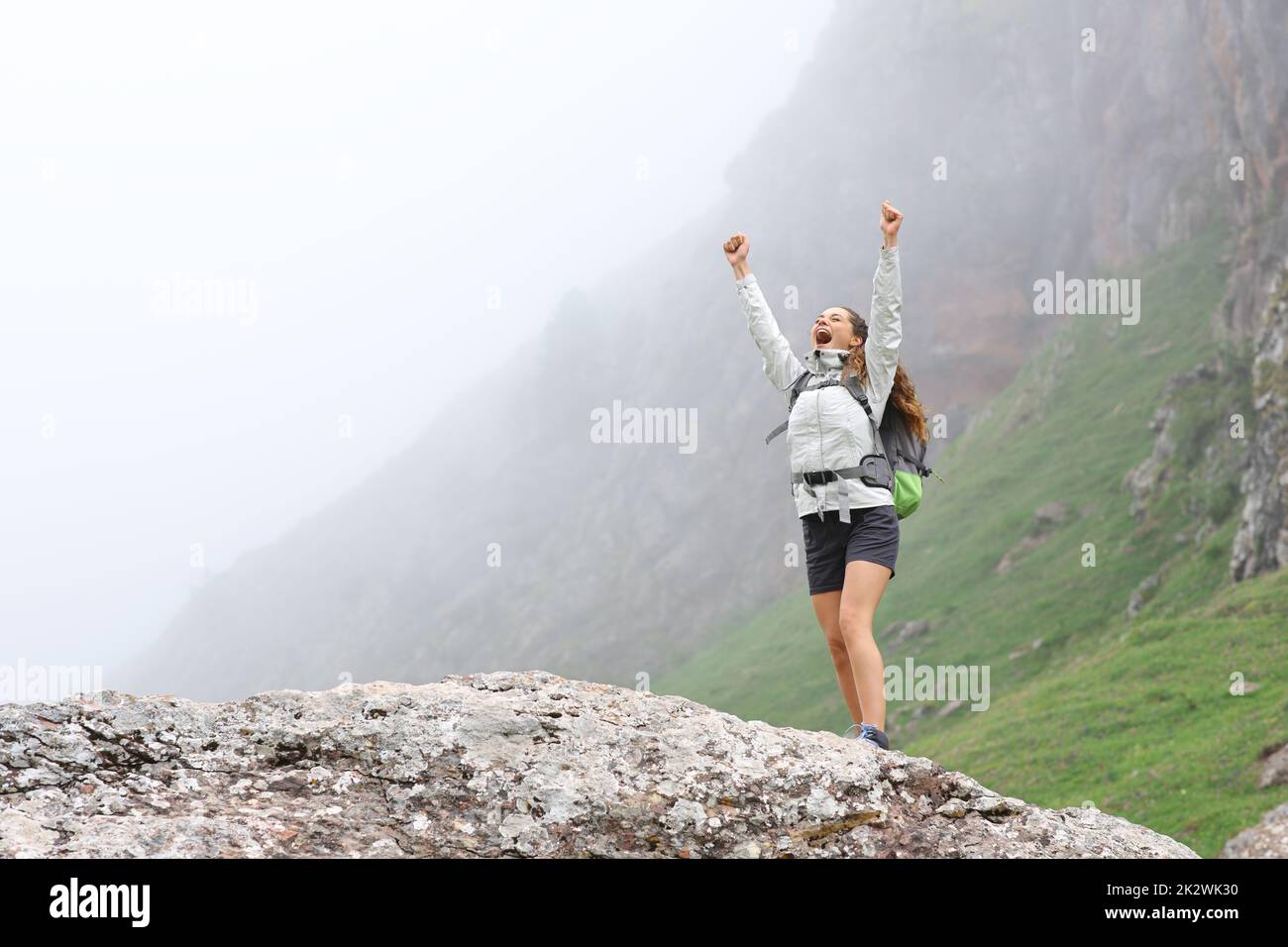 Trekker hebt die Arme im Berg an einem nebligen Tag Stockfoto