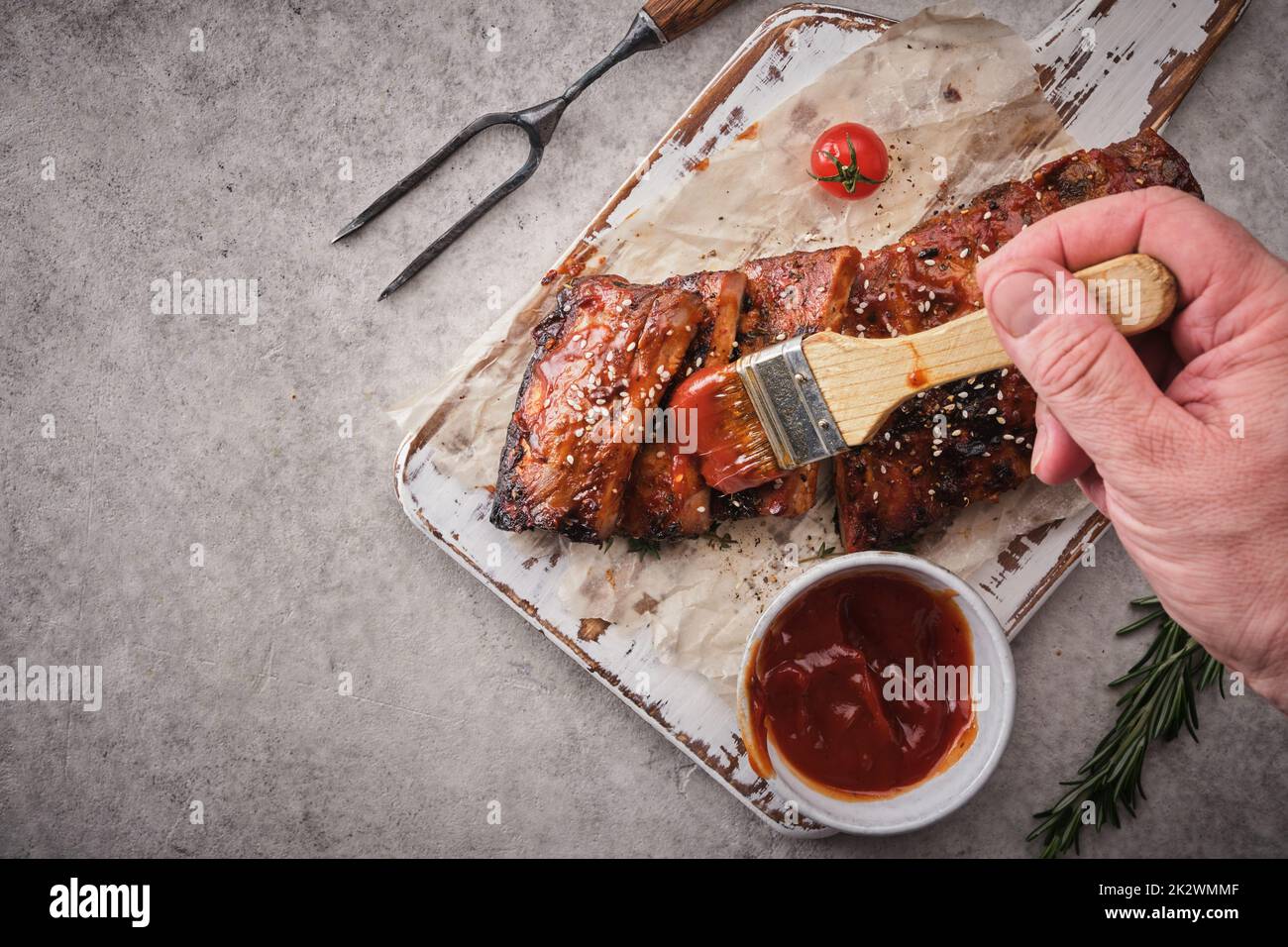 Köstliche gegrillte Rippchen mit einer scharfen Sauce gewürzt und auf dem Schneidebrett serviert. Stockfoto