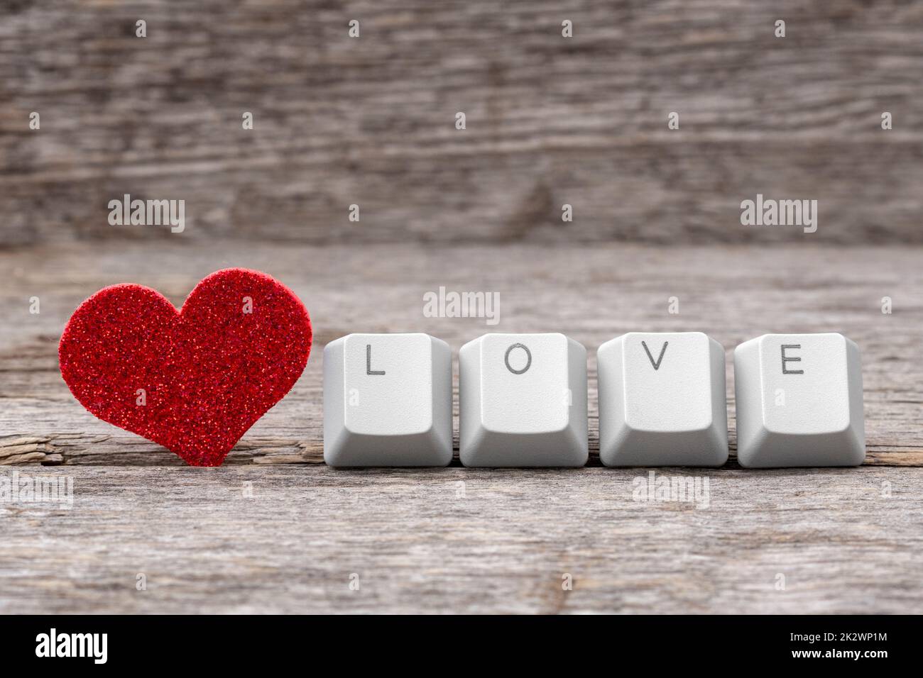 Rotes Herz und WORTLIEBE auf Tastaturtasten geschrieben Stockfoto
