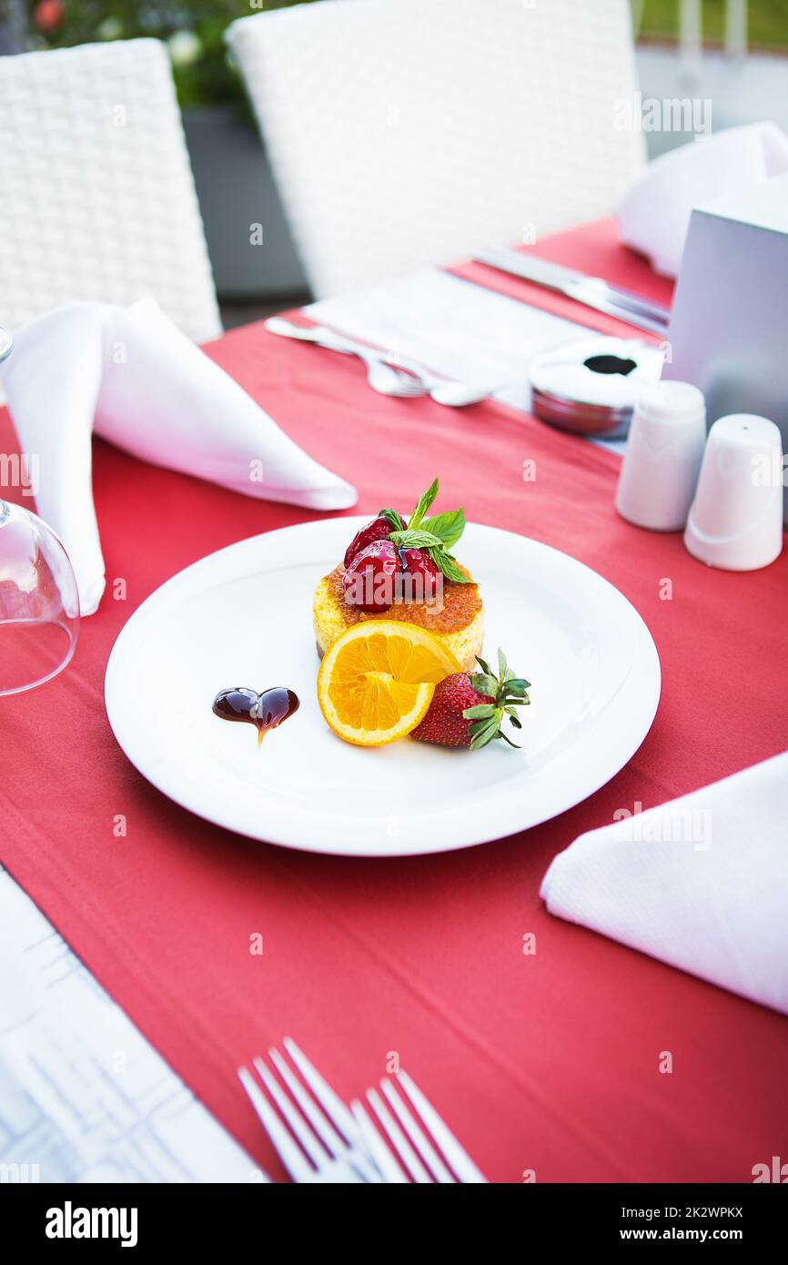 Mit Erdbeeren und Orange dekorierter Kuchenkuchen liegt auf einem weißen Teller Stockfoto