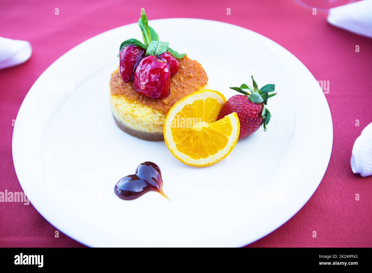 Mit Erdbeeren und Orange dekorierter Kuchenkuchen liegt auf einem weißen Teller Stockfoto