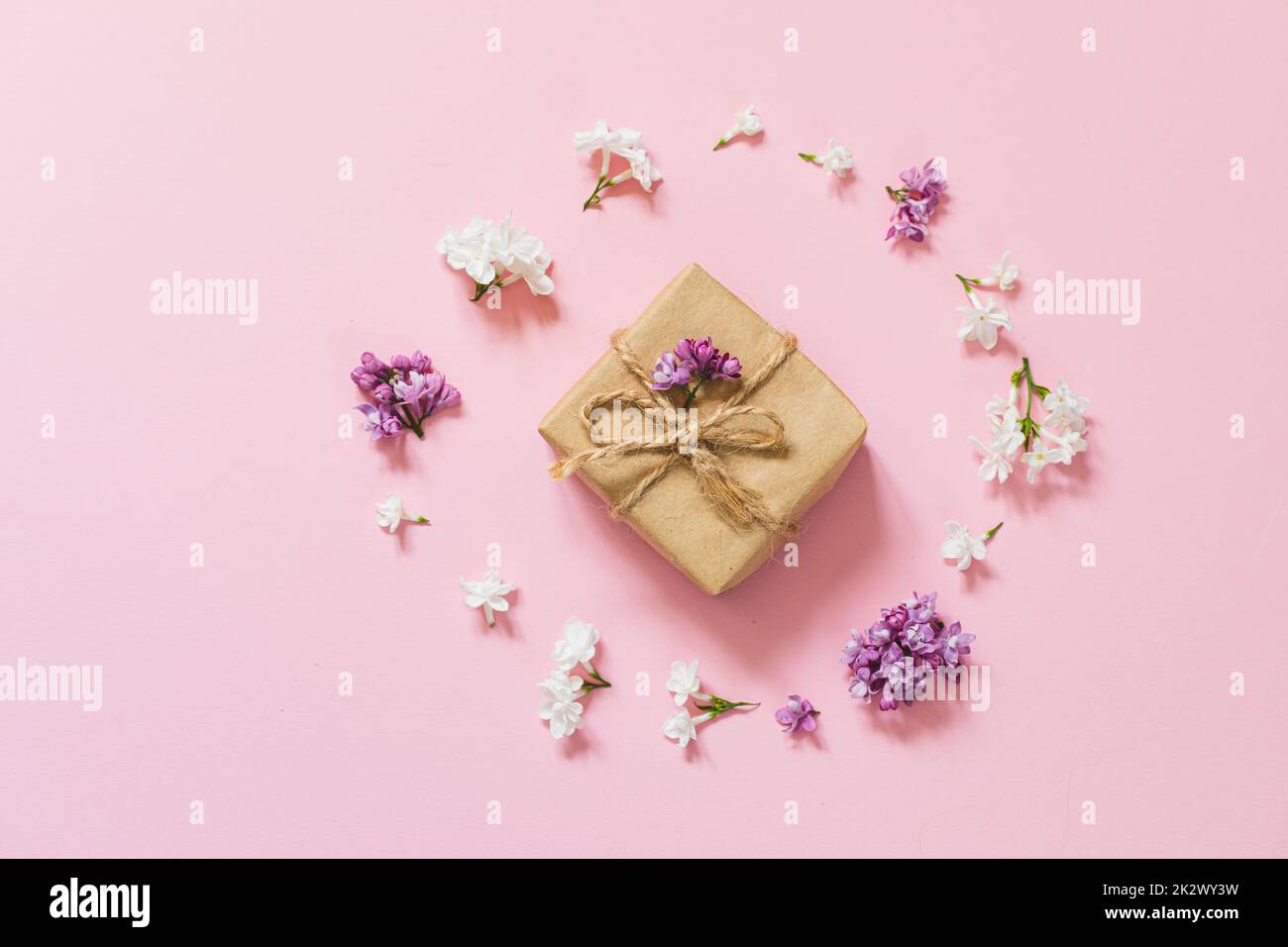 Fliederblumen mit umweltfreundlicher Geschenkbox aus Kraftpapier. Layout für kreative Glückwünsche. Frühlingsblumen-Konzept. Stockfoto