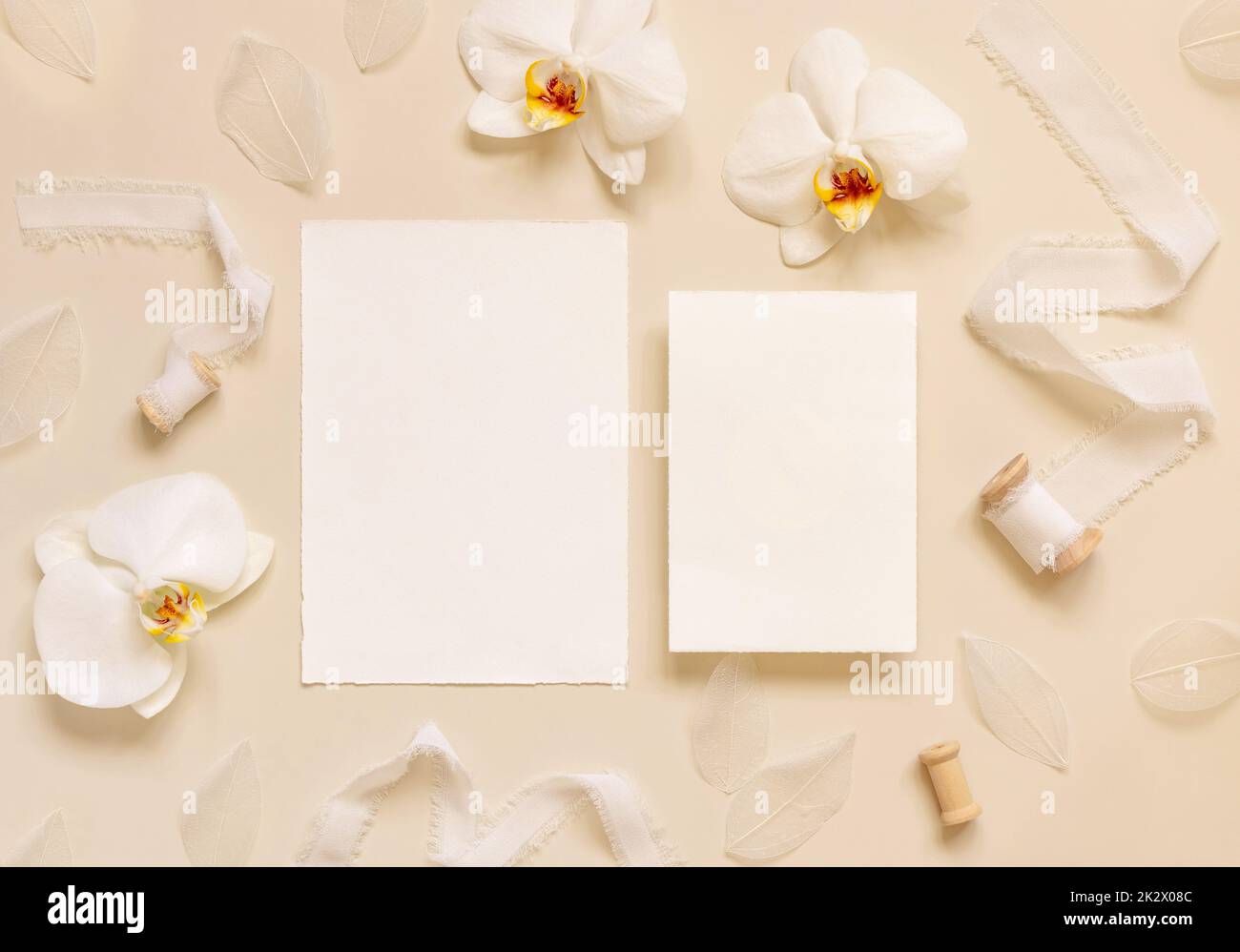 Hochzeitskarten neben weißen Orchideenblumen und Seidenbändern auf hellgelbem, Suite-Mockup Stockfoto