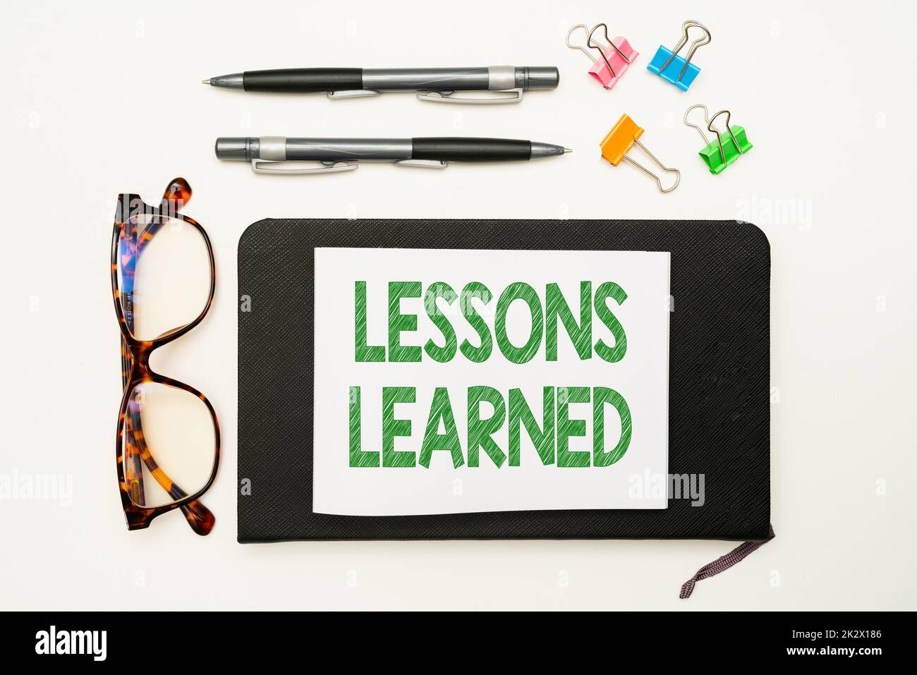 Text mit den gelernten Lektionen zur Inspiration. Geschäftskonzept fördern Sie den Austausch und die Nutzung von Kenntnissen aus Erfahrung Bürobedarf über Schreibtisch mit Tastatur, Gläsern und Kaffeetasse für die Arbeit Stockfoto
