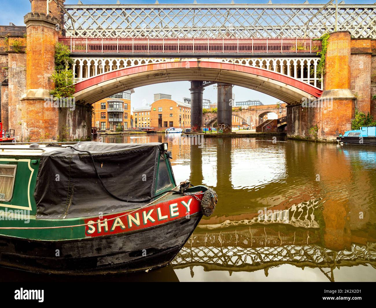 narrowboat, das auf dem Bridgewater Canal mit einer viktorianischen Eisenbahnbrücke und einem Viadukt von Castlefield in der Ferne festgemacht wurde. Castlefield. Manchester. VEREINIGTES KÖNIGREICH Stockfoto