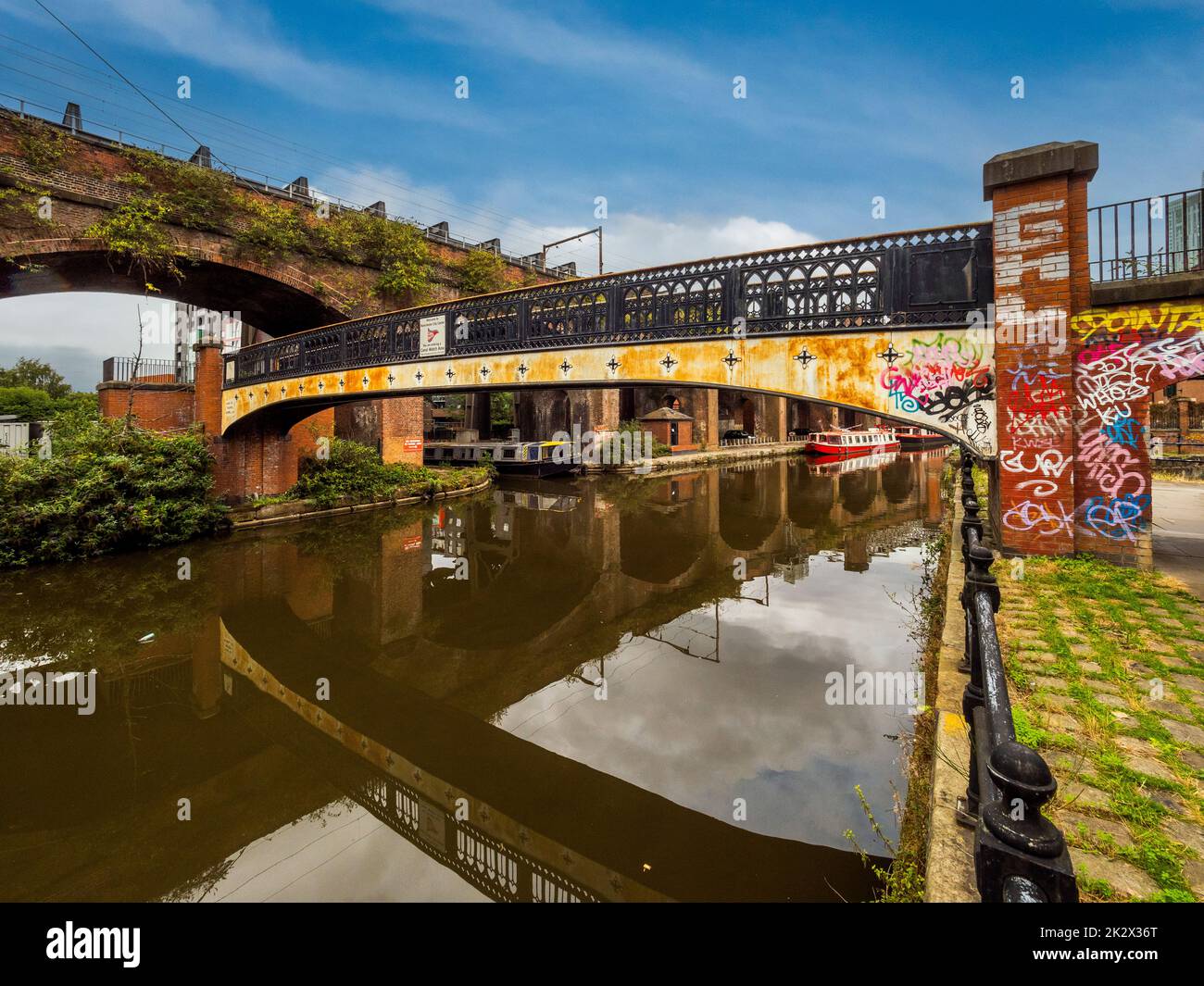 Fußgängerbrücke mit buntem Graffit über den Bridgewater-Kanal, der unterhalb des Bridgewater-Viadukts endet. Manchester. VEREINIGTES KÖNIGREICH. Stockfoto