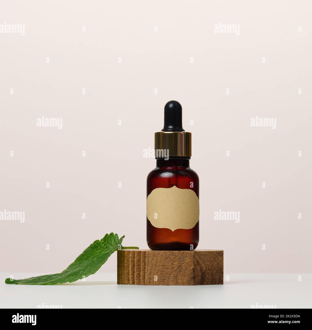 Eine braune Glasflasche mit einem Papieretikett und einer Pipette auf einem weißen Tisch. Behälter für Kosmetika Stockfoto