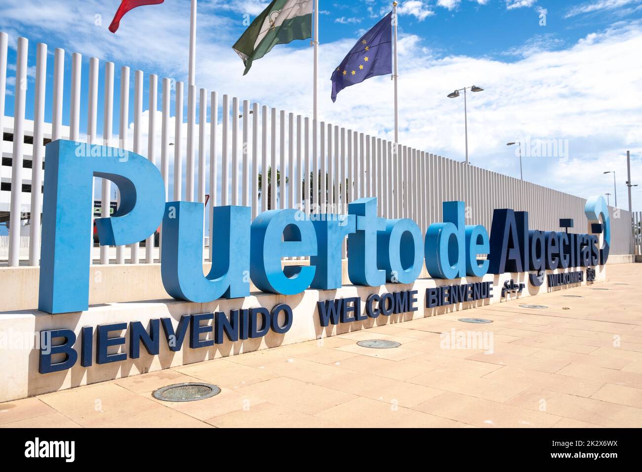 Das Begrüßungslogo von Puerto de Algeciras (Hafen von Algeciras) mit Fahnenmasten dahinter, das sich in der Nähe des Hauptfußeingangs für Passagiere befindet. Stockfoto