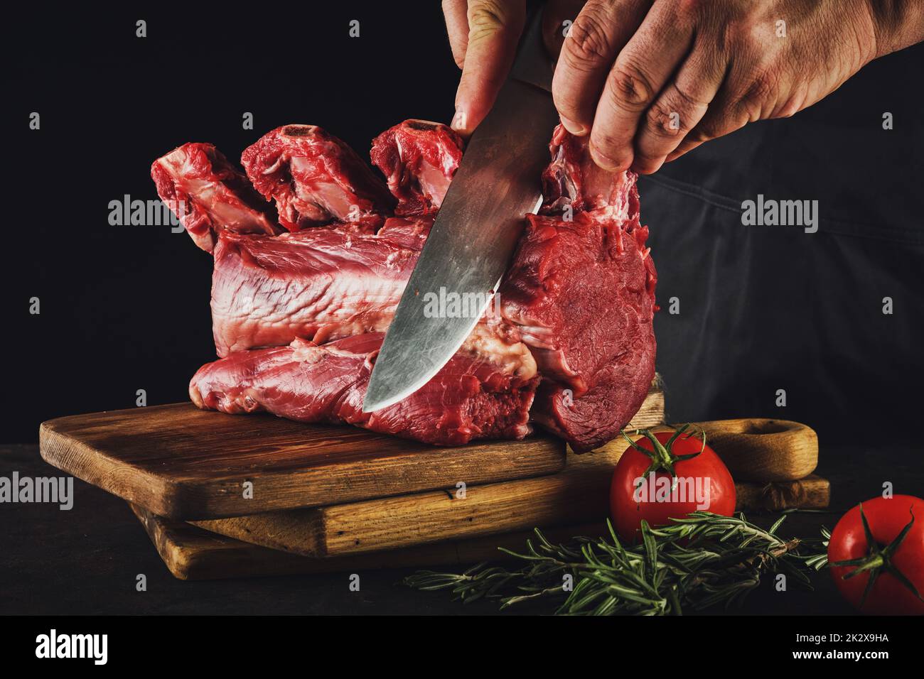 Männlicher Metzger schneidet rohes Rindfleisch. Stockfoto