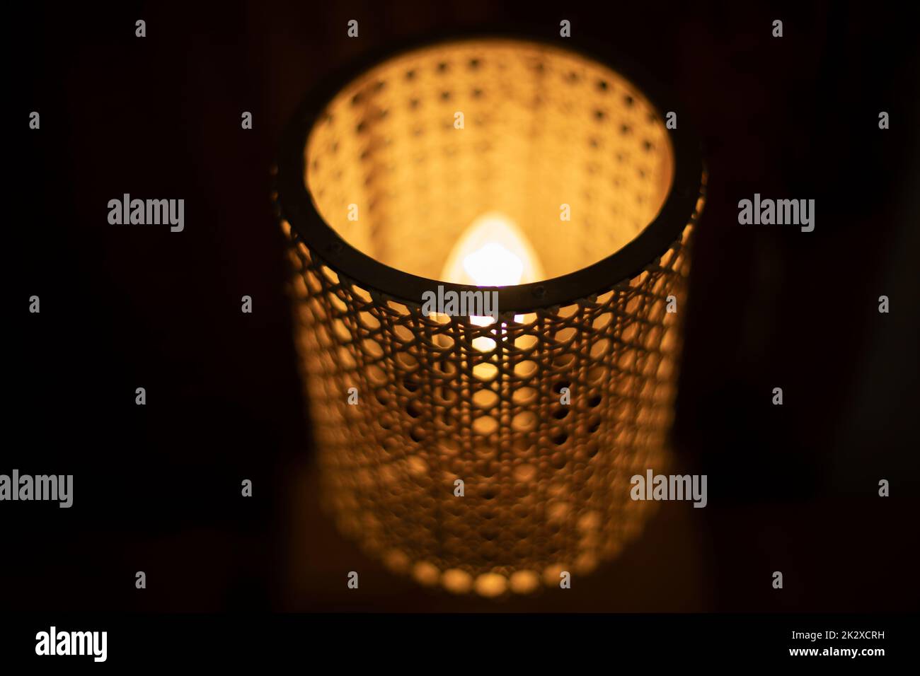 Lampe im Dunkeln. Holzlampenschirm um die Glühlampe. Stockfoto